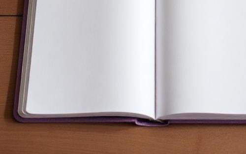 Quiet editorial: open notebook with an empty page and visible paper edge on wooden table, soft natural light, muted tones